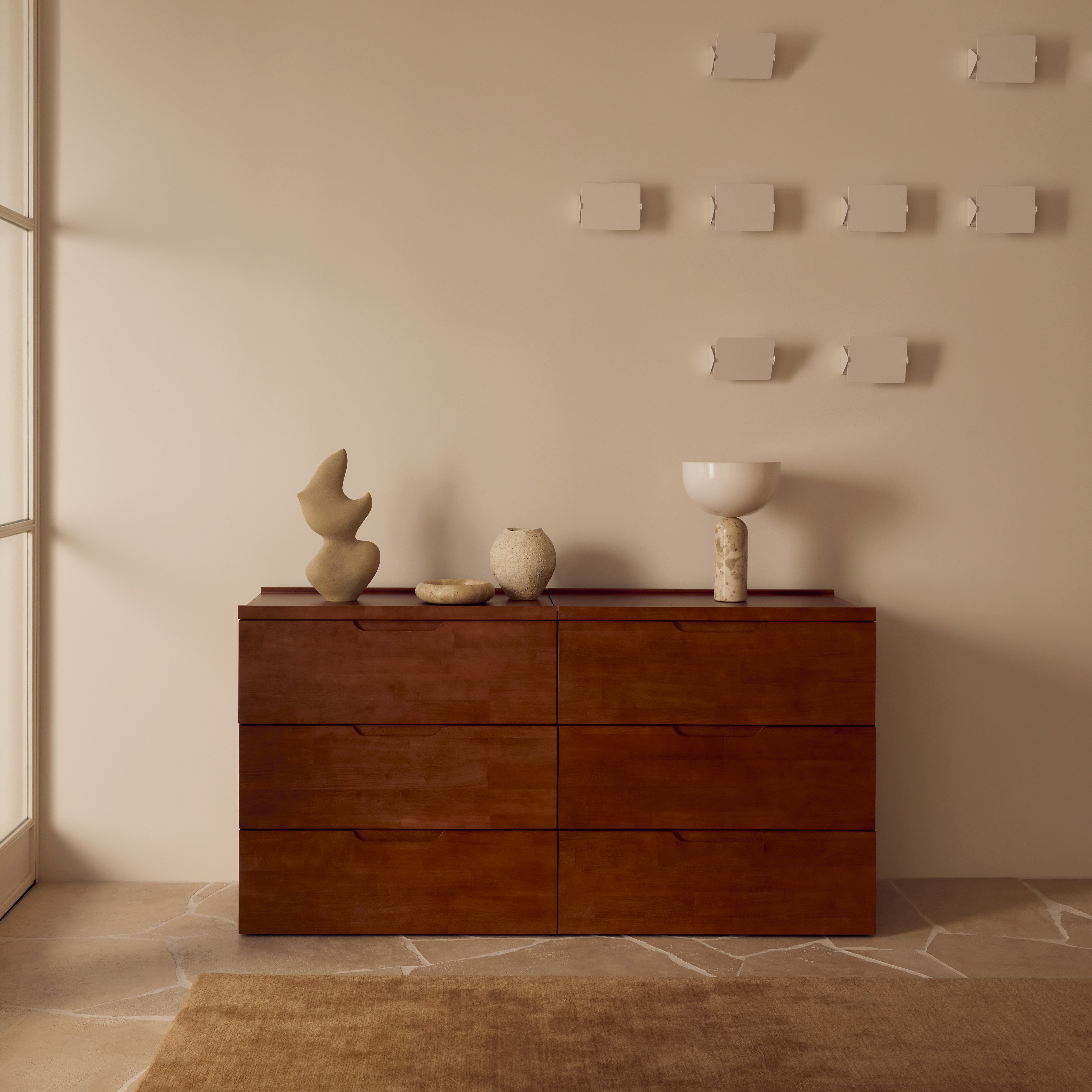 Wooden dresser with decorative items against a beige wall