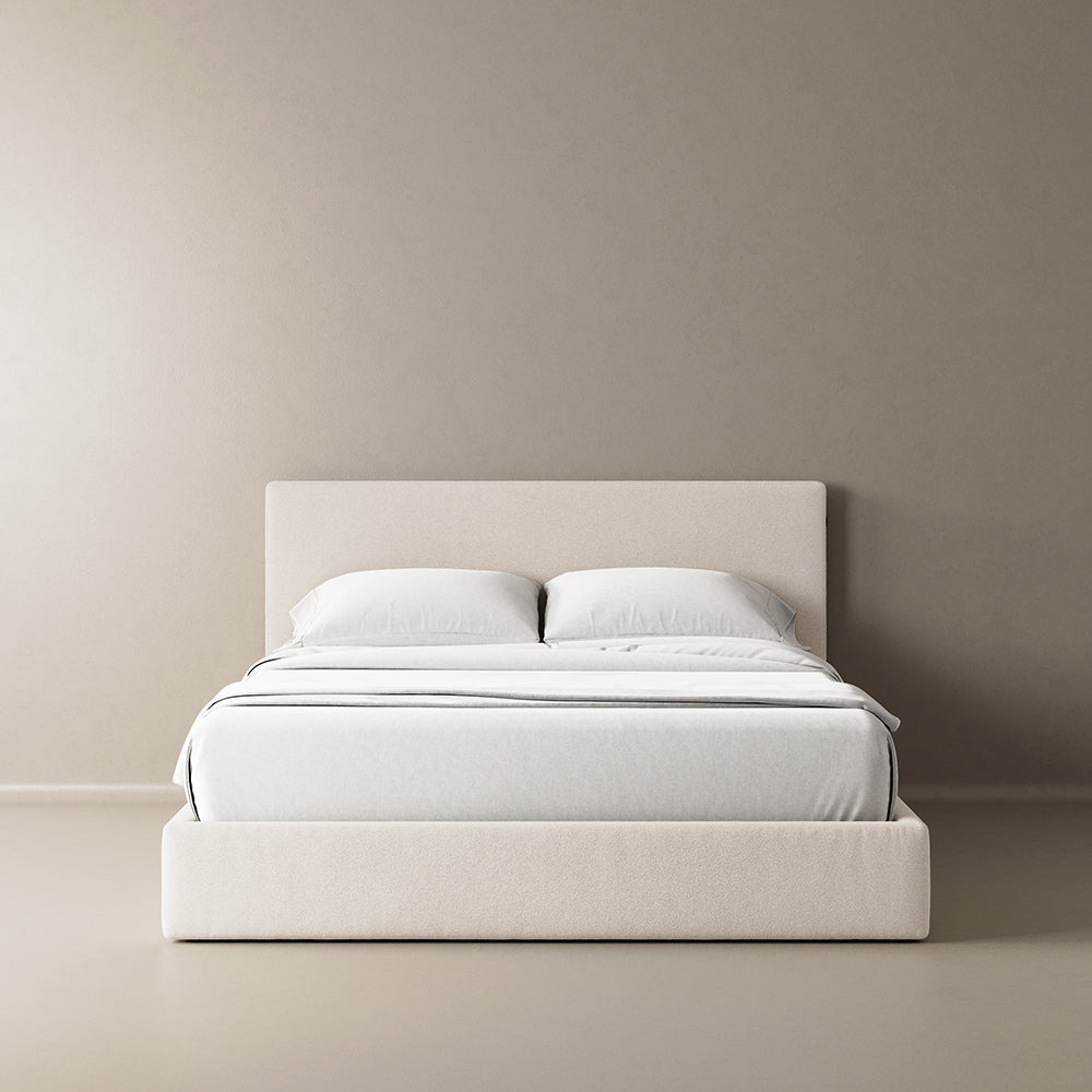 A light beige, cushioned bed frame with a simple, modern design, fully assembled and ready for use.