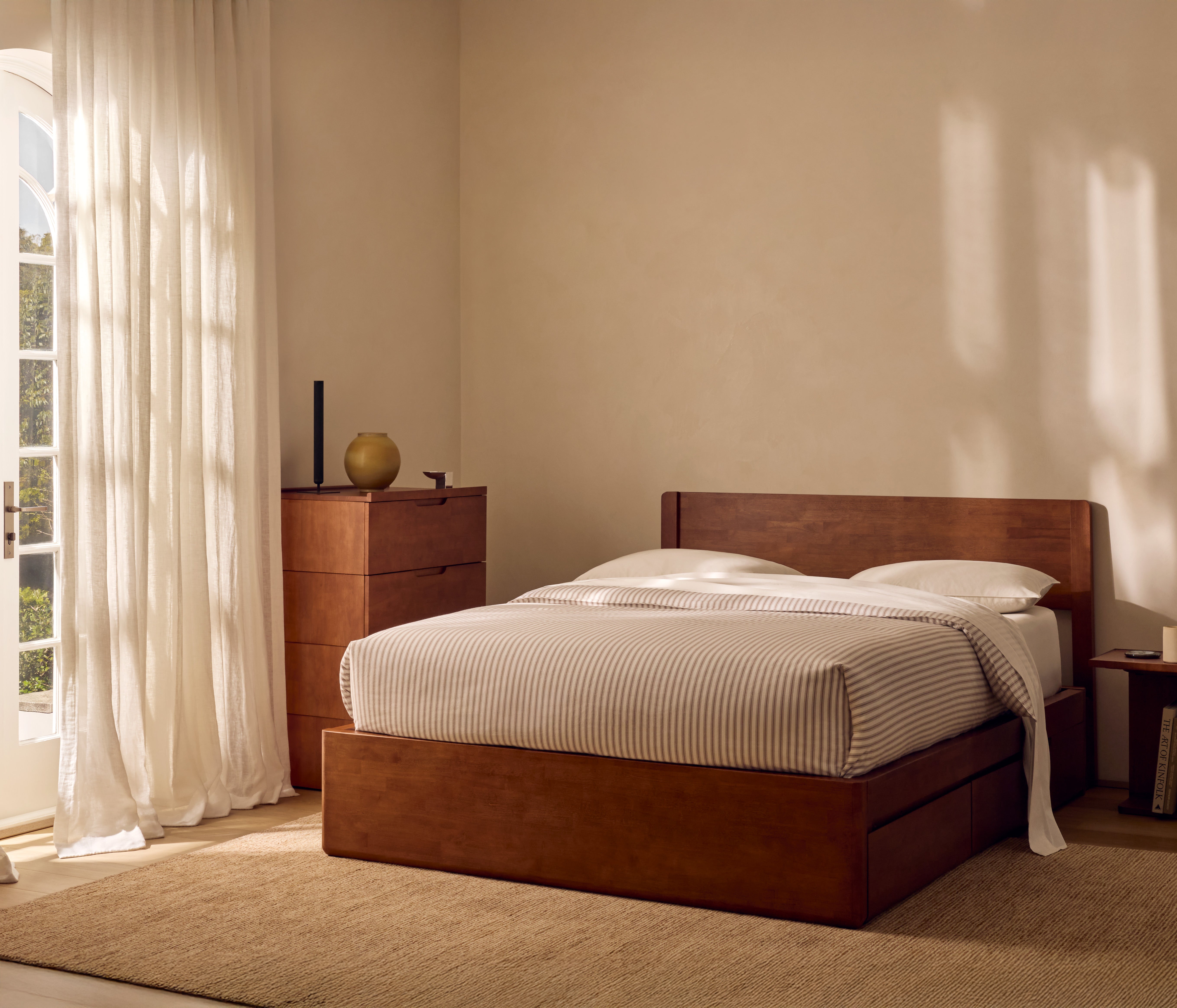 Bedroom with wooden bed and dresser against a beige wall